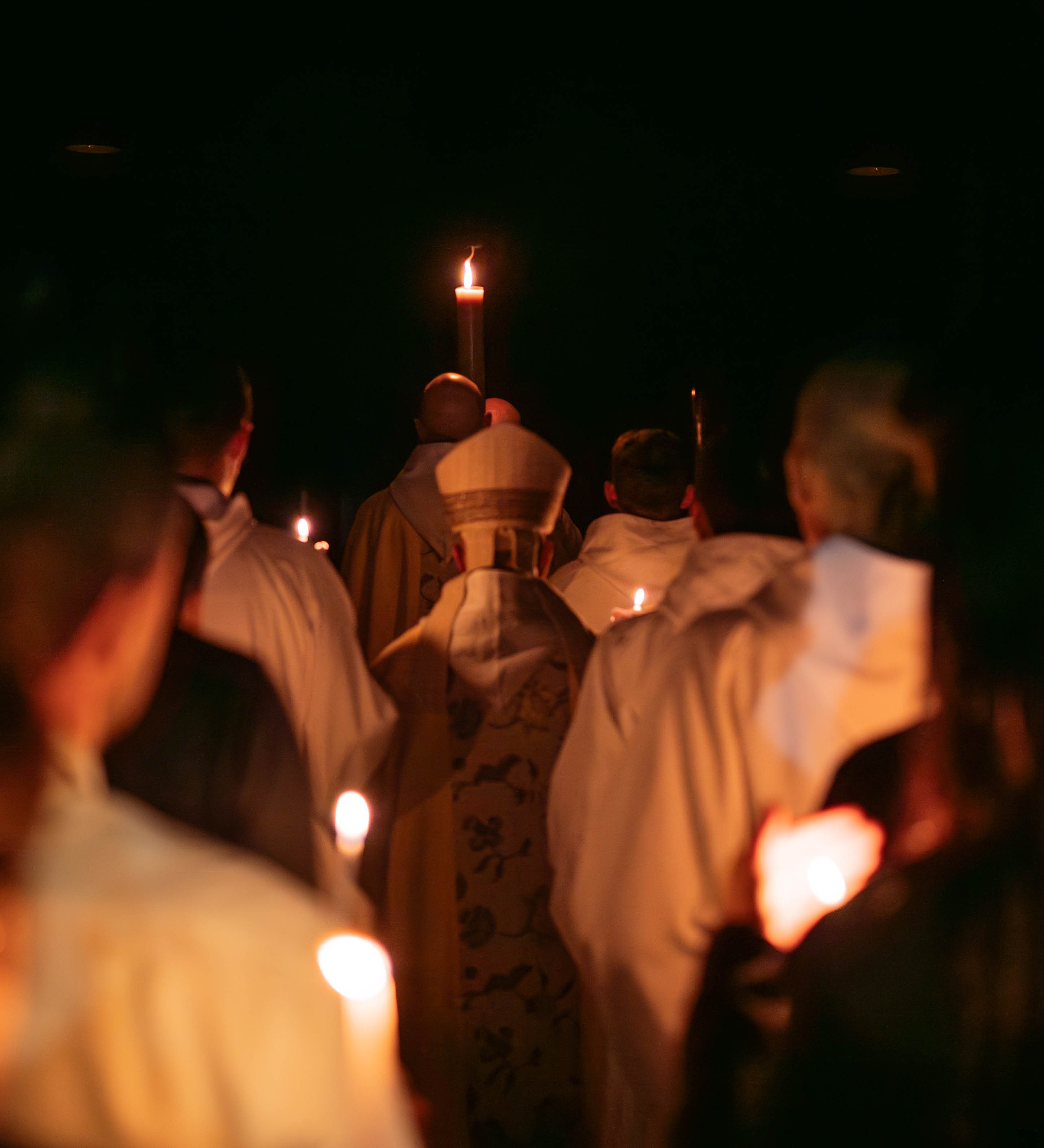 Procissão de entrada com velas acesas, atrás do círio pascal